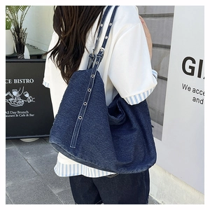 Detailed view of wide strap with metal grommets on a blue denim tote bag for women