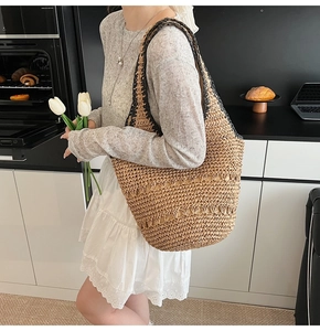 Close-up of natural straw tote bag featuring wavy woven texture and black shoulder straps