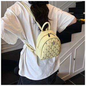 Detail of cream quilted mini backpack with star emblem and silver studs on model