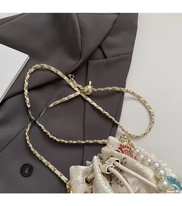 Detail of embroidered floral bucket bag with pearl handle and chain strap in silk fabric