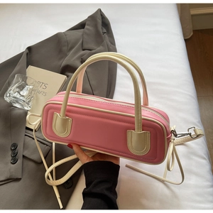 Pink baguette bag with beige trim and quilted pattern held against a grey blazer outfit