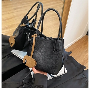 Détail d'un sac seau noir en cuir grainé avec un petit pendentif éléphant marron chic