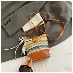 Detail of woven straw bucket bag with brown leather trim and golden twist-lock closure
