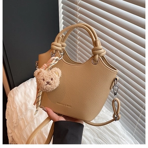 Detailed macro view of litchi-grain leather texture with fashion embossing and plush bear charm