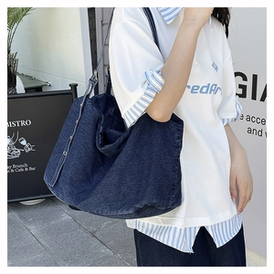 Macro detail of casual dark blue denim tote bag with wide strap and metallic buckle