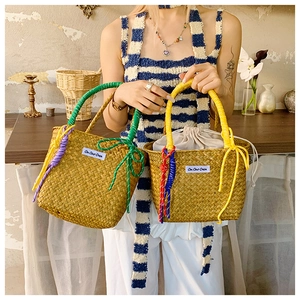 Detail of woven straw bucket bag featuring colorful rope knots and a drawstring inner pouch