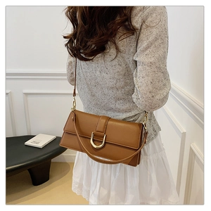 Détail d'un sac à bandoulière en cuir marron avec boucle dorée en D et sangle ajustable