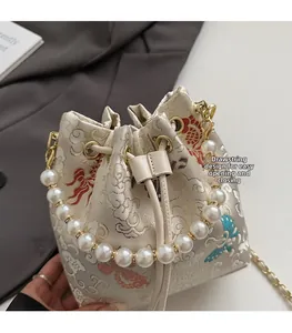Close-up of Chinese style bucket bag with gold cloud embroidery and pearl handle
