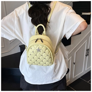 Detail of light yellow quilted mini backpack with star patch and silver studs