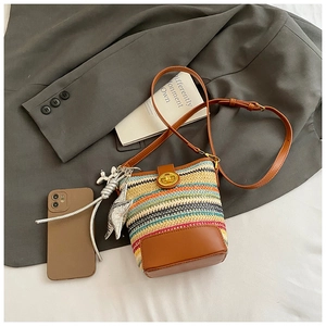 Detailed close-up of rainbow striped woven bucket bag with leather base and gold lock