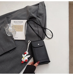 Detail of black pebbled leather crossbody phone bag with cute white duck plush charm