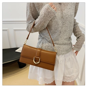 Détail d'un sac à bandoulière en cuir marron avec boucle en D dorée et fini brillant