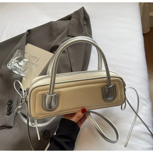 Detail of a contrast baguette bag with silver handles on a minimalist background