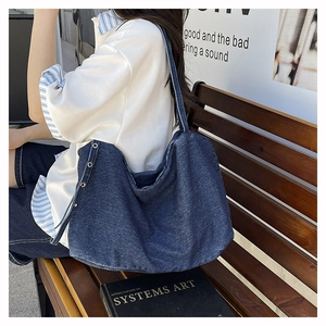 Detail view of large navy denim tote bag with metal eyelets on a wooden bench outdoors