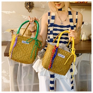 Detailed close-up of straw bucket bag featuring colorful rope accents and interior drawstring