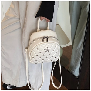 Detailed shot of white quilted mini backpack with star emblem and silver stud accents