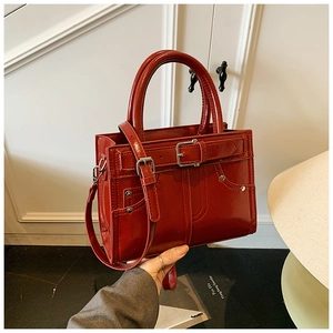 Détail du sac à main rouge brillant avec boucle en métal et bandoulière réglable