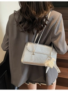 Silver metallic shoulder bag with pleated texture and pearl heart pendant on a model