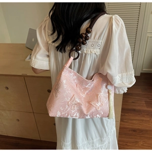 Détail du sac jacquard rose avec broderie papillon et bandoulière en perles de bois