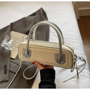 Detailed close-up of cream PU leather baguette bag with metallic silver piping trim