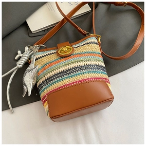 Detail view of woven bucket bag with leather trim and balloon dog charm on top of magazines