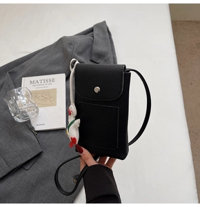 Close-up of black pebble leather crossbody phone bag with cute white duck charm decoration