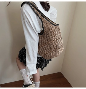 Detailed side view of a large woven straw hobo bag showing texture and black trim edges