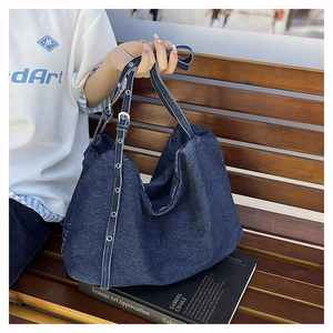 Detail of navy denim tote bag with contrast white stitching and metal eyelet strap