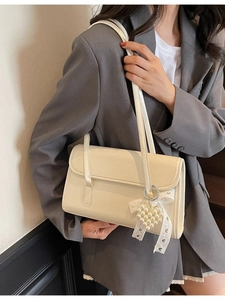 Chic beige ruched shoulder bag with pearl heart charm and lace bow on a model