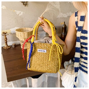Close-up of straw woven bucket bag with tricolor rope knots and canvas drawstring lining