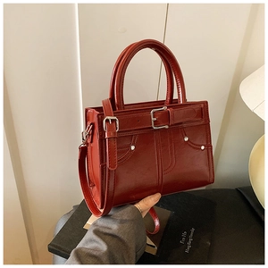 Détail du sac à main en cuir verni bordeaux avec boucle vintage et rivets argentés
