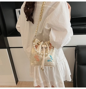 Détails de broderie chinoise sur sac seau en satin crème avec poignée en perles et chaîne