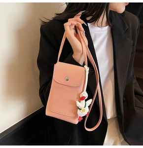 Detail of pink lychee textured leather mini crossbody bag with a cartoon duck charm