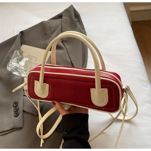 Detail of burgundy and cream contrast baguette bag with silver zipper and matte leather