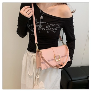 Mannequin portant un sac bandoulière rose avec boucle en D dorée sur tenue noir et blanc