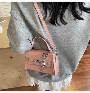 Pink textured handbag detail featuring silver metal lock and cute rabbit charm accessory