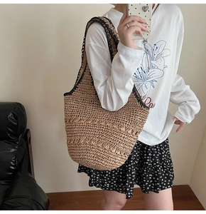 Straw woven tote bag with hollow design and black trim shoulder straps for beach vacations