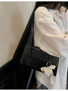 Minimalist black patent leather shoulder bag with pearl heart charm and lace bow detail