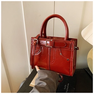 Détails d'un sac à main rouge brique brillant avec boucles rétro et rivets métalliques