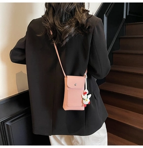 Pink lychee texture crossbody bag with cute duck charm shown on model in black suit