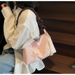 Détail du sac rose avec broderie papillon et poignée en perles avec pompon chic