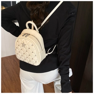 Detail view of mini quilted cream backpack with rhinestone star accents on model