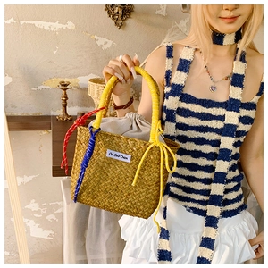 Detail of handwoven straw tote with colorful rope handles and On Our Own fabric label