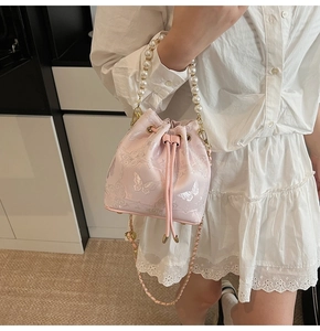 Détail du sac seau rose clair à cordon avec broderie florale et poignée en perles