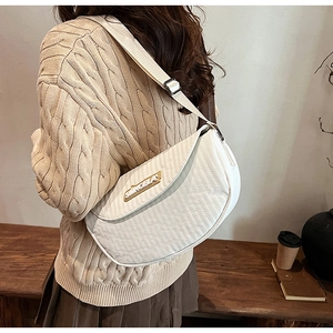 Close-up of ivory quilted saddle bag with metal logo and stylish crossbody strap