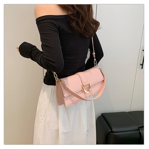 Détail d'un sac à bandoulière rose avec une boucle métallique dorée en U sur le rabat