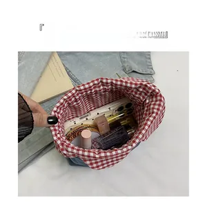 Top view of denim drawstring bucket bag showing interior storage with red checkered lining