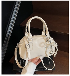 Macro shot of cream oil wax leather texture with pearl bow charm on a retro satchel bag