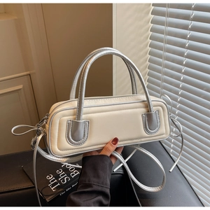 Close-up of contrast color baguette bag featuring silver handles and zip closure detail