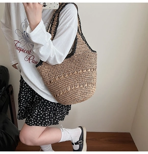 Detail of hand-woven straw tote bag with black contrast trim and hollow-out pattern